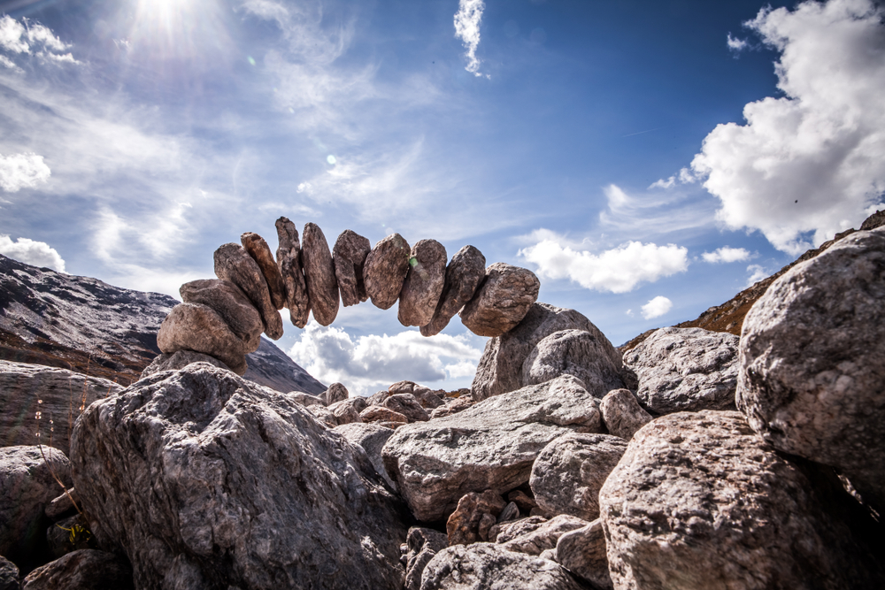 an arch made of stones with sky behind